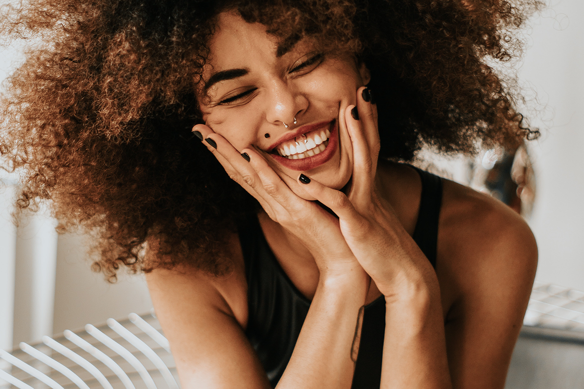 Closeup of joy-filled girl with a beautiful smile wearing a black tank top and matching black nail polish.